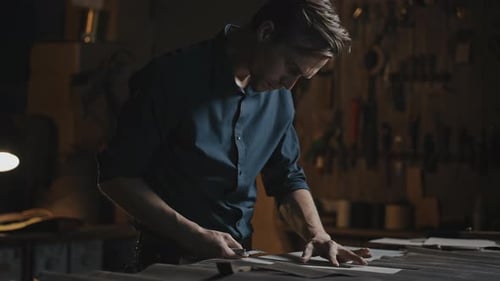 Man Cutting Material With Blade in Workshop