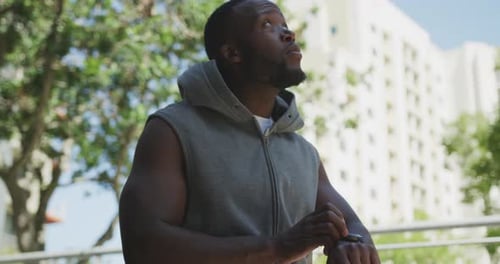 Man Checks Smartwatch and Puts on Hoodie