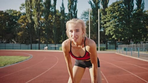 Girl in a Sports Uniform is Breathing Heavily with Her Hands on Her Knees
