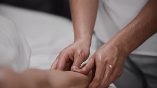 Man Massages Woman's Hand and Arm with Oil