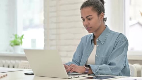 Young Adult Works on Laptop at Desk