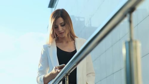 Woman Using Phone Near Modern Building During Day