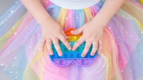 Child Plays with Colorful Pop-it Fidget Toy