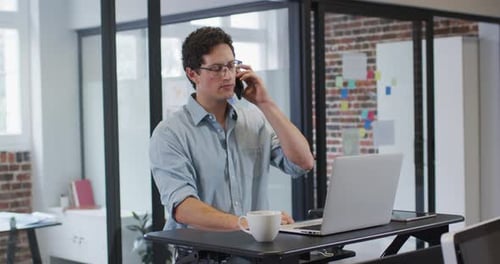Man On Phone Uses Laptop at Standing Desk
