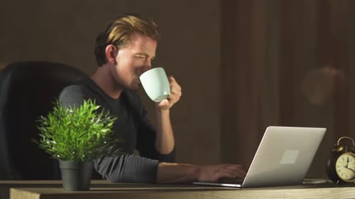 Junger blonder Geschäftsmann arbeitet am Notizbuch im modernen Büro und trinkt Kaffee