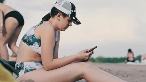 Young Woman Uses a Smartphone on the Beach