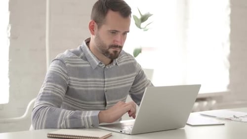 Man Working on Laptop in Bright Modern Office