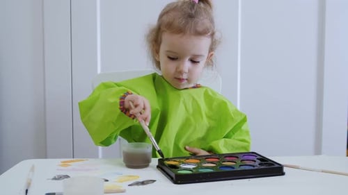 Child Concentrating on Painting at Table Indoors