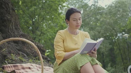 Woman Reading a Book During an Outdoor Picnic