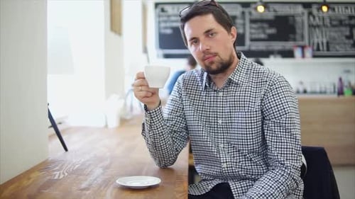 Male Cafe Visitor Enjoying Cup of Coffee. He Holding It