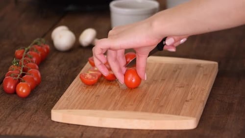 Person Cutting Tomatoes on Wooden Cutting Board
