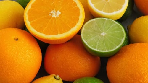 Halb geschnittene saftige Limette auf Zitrusfrucht-Hintergrund, viel Zitrone, Orangen und Limetten Ansicht von oben