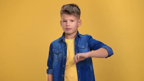 Portrait of Trendy Male Teen Showing Thumbs Down Frowning Shaking Head Posing Isolated on Orange