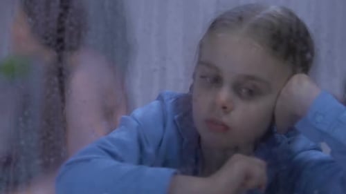 Hija mirando en la ventana lluviosa, padres peleando en segundo plano, conflicto
