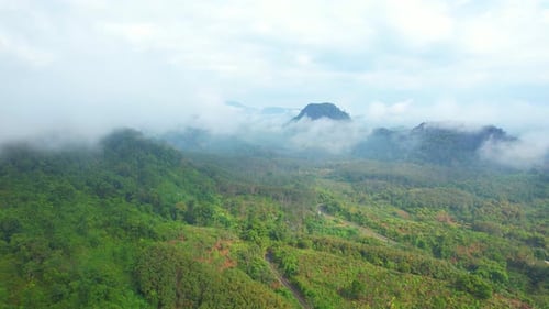 4K Aerial view from a drone flying above rural clouds, road in a tropical forest in Thailand