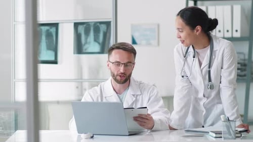 Positive Male and Female Doctors Posing for Camera at Workplace in Clinic