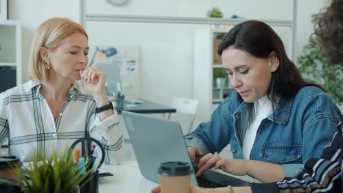 Women Collaborating on Laptop in Modern Office