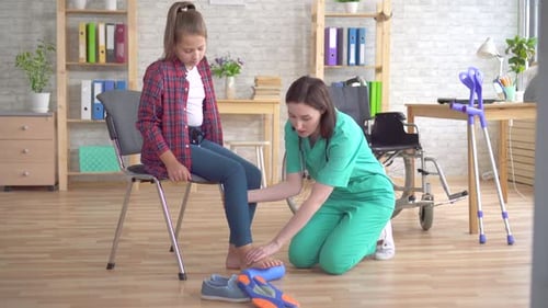 Arzt hilft bei der Rehabilitation Um das Bein mit Hilfe einer Rolle eines Teenagers in einem