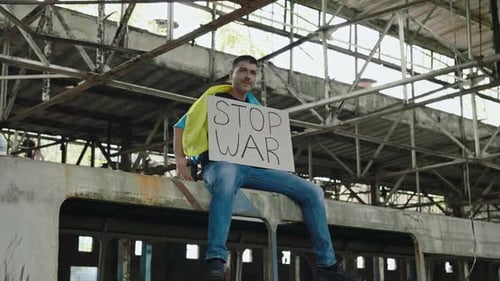 Man Sits On Abandoned Train Holding "Stop War" Sign