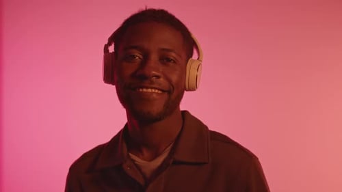 Man Enjoying Music with Headphones in Pink Light