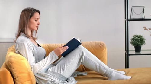 Woman Relaxing on Sofa Reading a Book