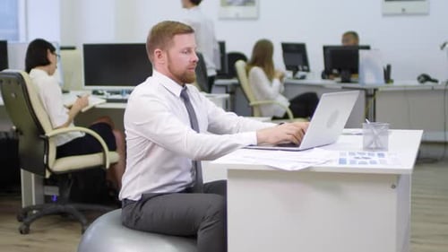 Homme assis sur Fitball et travaillant
