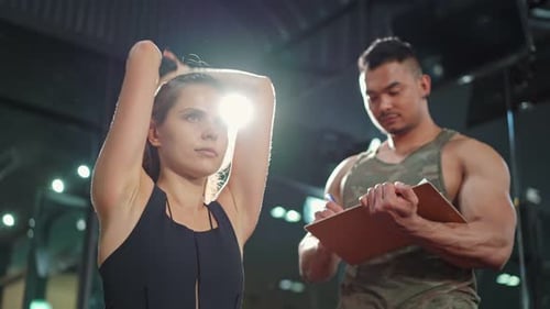 Coach teach Caucasian girl lift weight dumbbell for biceps to improve strength and maintain muscle.