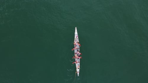 Sport Canoe with a team rowing on tranquil water, Aerial view.