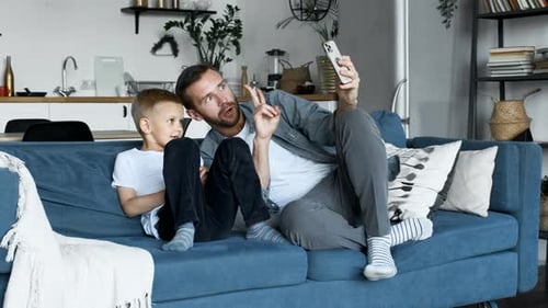 Father and Son Taking Selfie on Couch