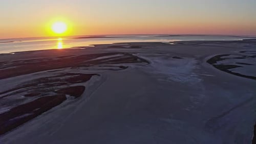 Pantano arenoso junto a un hermoso lago y una colorida puesta de sol