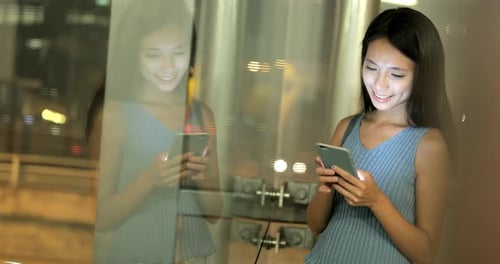 Woman using mobile phone in the city at night