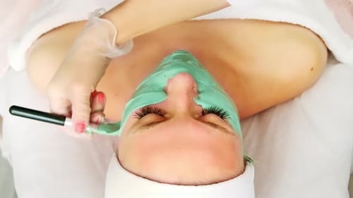 Woman Receiving a Green Facial Mask Spa Treatment