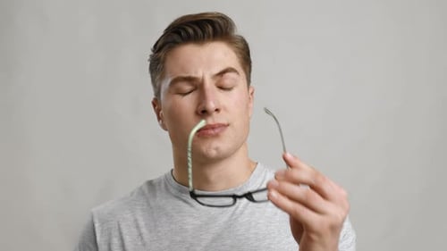 Young Tired Man Taking Off His Glasses and Rubbing His Eyes Grey Studio Background Slow Motion