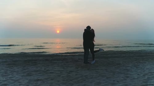 Silhouetted Couple Embrace on a Beach at Sunrise