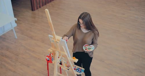 Artist Mixes Paint on the Palette and Paints on Canvas