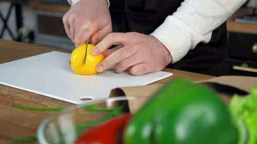 Hände Chefkoch Mann in Schürze steht neben Tisch schneidet Zitrone an Bord in der heimischen Küche