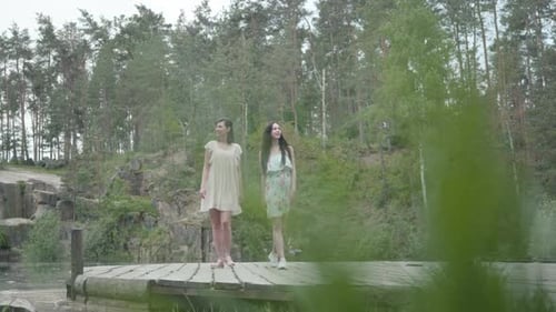 Two Adorable Women Wear Summer Dresses Standing in the Top of Rock and Looking at Amazing View