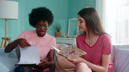 Two Young Women Study Together on Couch