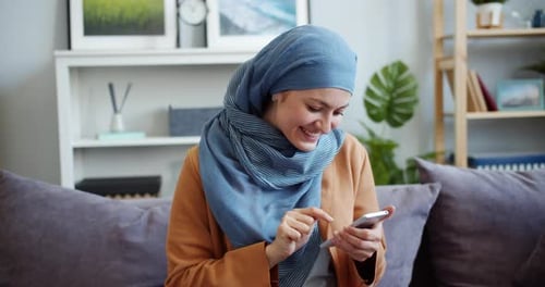 Smiling Woman Using Smartphone on Couch Indoors