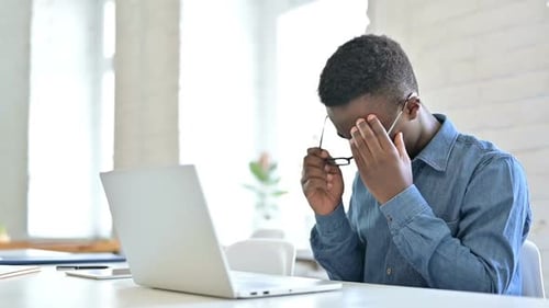 Hardworking Young African Man with Laptop Having Headache