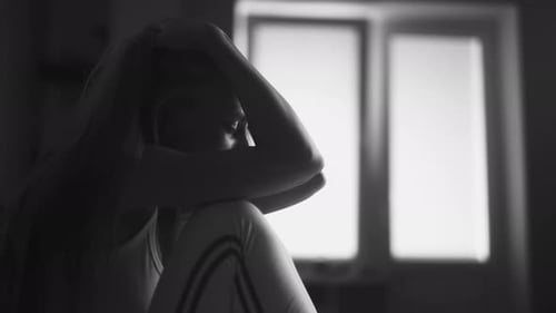 Distressed Woman Sitting Indoors in Black and White
