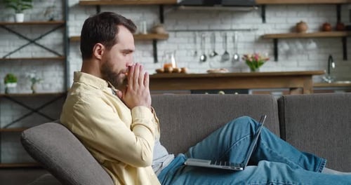 Unpleasantly Surprised and Shocked Young Man By the Bad News Seen on the Laptop Screen While Working