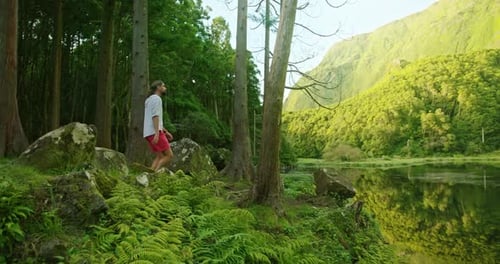 Un homme caucasien bénéficie d'une belle vue panoramique sur le lac entouré de plantes