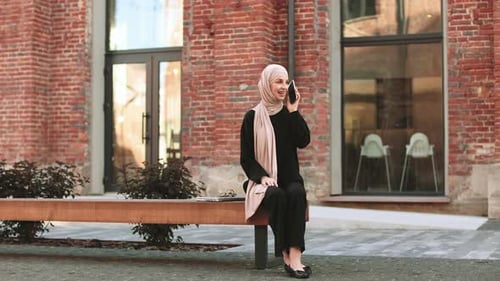 Young Smiling Happy Muslim Woman Doing Video Call Using Smartphone at the City