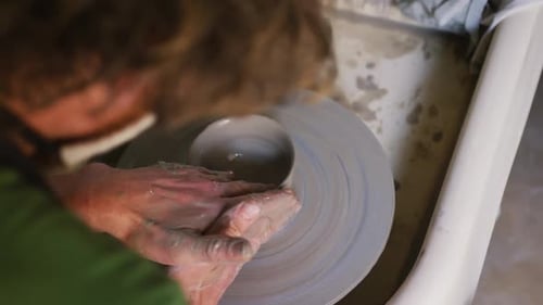 Vue rapprochée d'un potier créant de la poterie sur une roue de potier dans un atelier de poterie