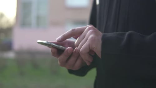 Mann geht die Straße entlang und tippt auf einem Smartphone
