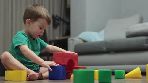Little Kid Boy Building Tower Garage From Colorful Plastic Cubes Blocks on Floor