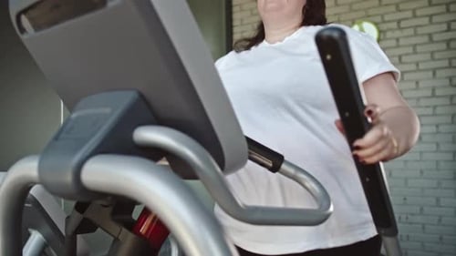 Chubby Woman Using Elliptical Trainer