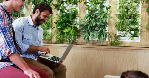 Adults Work Together with Technology in Bright Office