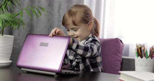 Little Child Opens Laptop at a Table